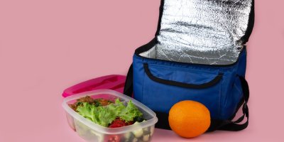 Termotaška s otevřeným víkem, před ní krabička s jídlem a pomeranč