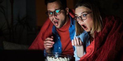 Mladý pár sleduje s otevřenou pusou film a jí popcorn