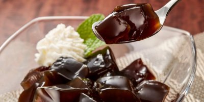 Želé kostky na lžíci, v pozadí kostky se šlehačkou v misce