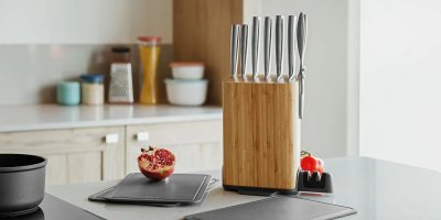 Sada nožů a granátové jablko na podložce v kuchyni