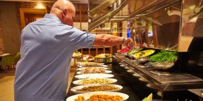 Muž si v hotelovém bufetu nabírá jídlo z mís