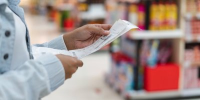 Záběr na ženu, která si prohlíží účtenky v obchodě.