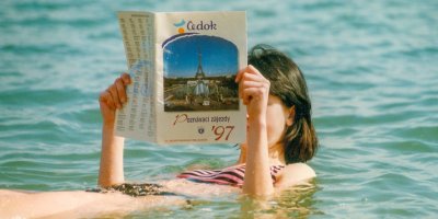 Žena plave ve vodě a čte si Čedok katalog z roku 1997