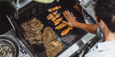 Muž griluje maso a špízy