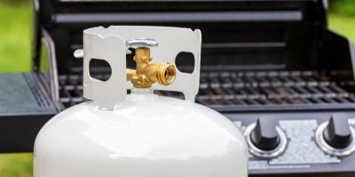 Bílá plynová bomba stojí před grilem