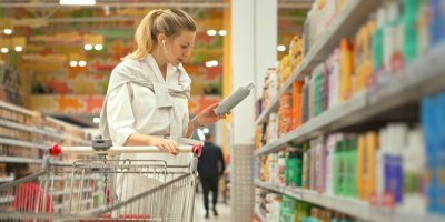 Žena si čte etiketu šamponu v supermarketu