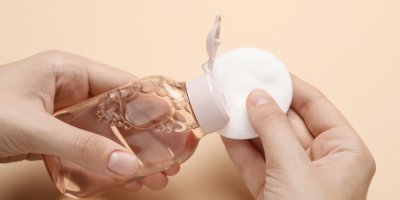 Ruce dávají micelární vodu s lahvičky na tamponek