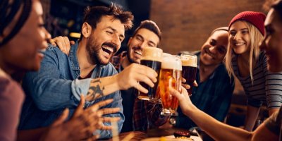 Banda lidí si přiťukává pivem a směje se