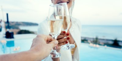 Žena a muž si připíjí bílým vínem u bazénu