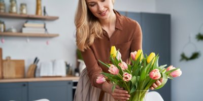 Žena aranžuje květiny ve váze