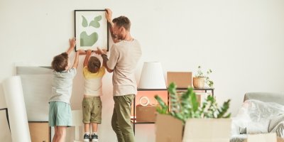 Otec s dětmi věší obraz na stěnu