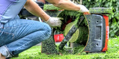 Muž kontroluje secí nůž sekačky