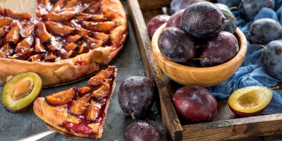 Miska a bedýnka švestek vedle švestkového koláče