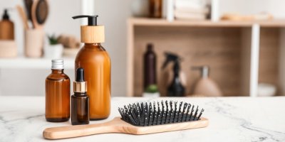 Vlasová kosmetika v lahvičkách a hřeben na vlasy
