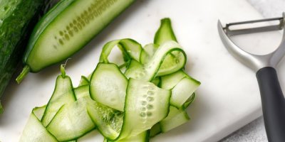 Kus okurky a z ní nakrájené tenké plátky