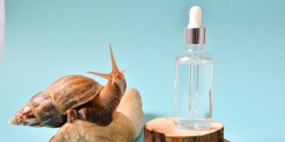 Šnek na kameni, vedle čiré sérum v lahvičce s kapátkem