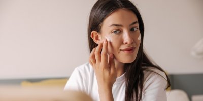 Mladá žena si dává krém na tváře