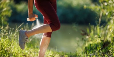 Žena si stříká na nohu repelent