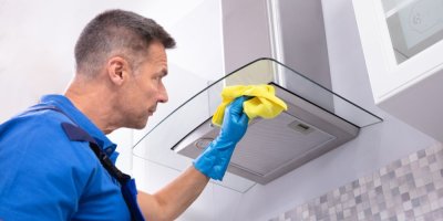 Muž v gumových rukavicích čistí digestoř