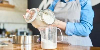 Žena sype cukr do odměrky.