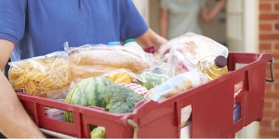 Muž nese bedýnku s nákupem