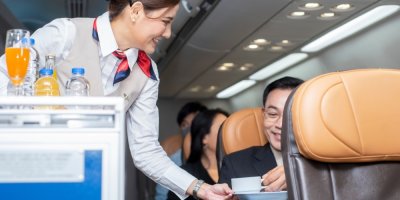 Letuška podává cestujícímu v letadle hrnek
