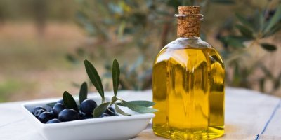 Černé olivy v bílé misce a vedle stojící olivový olej