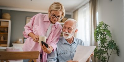 Starší žena a muž si prohlíží něco na chytrém telefonu.