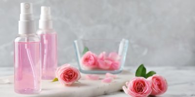 Růžová voda ve dvou malých plastových rozprašovačích, růže, okvětní lístky v misce