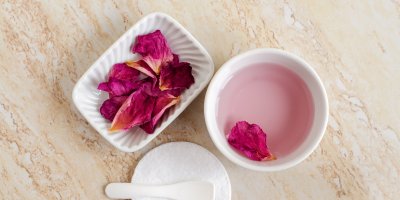 Růžová voda v misce, mokré okvětní lístky v druhé misce, špachtle