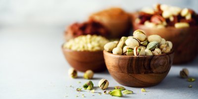 Dřevěné misky s pistáciemi a dalšími druhy ořechů
