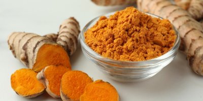 Nakrájený kořen kurkumy a mletý kurkumový prášek v misce