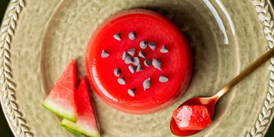 Melounové želé  na talířku, vedle kousky melounu a lžička