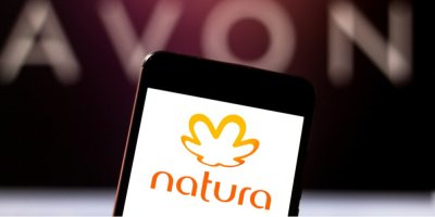 Logo firmy natura na displeji smartphonu, v pozadí nápis Avon