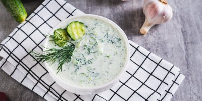 Tzatziki v misce, zdobené snítkou kopru, velde položený česnek