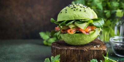 Burger se zelenou bulkou, plátky uzeného lososa a zeleninou