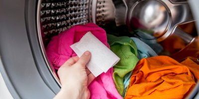 Ruka dává do pračky ubrousek na praní