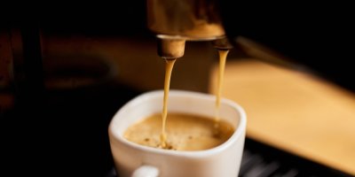 Detail kávy tekoucí z kávovaru do hrnku