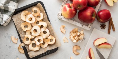 Plech se sušenými kolečky jablek a čerstvá jablka vedle něj