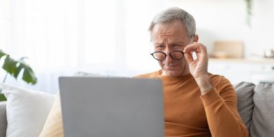 Muž si drží brýle a dívá se do notebooku