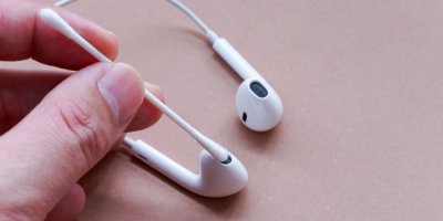 Ruka čistí sluchátko vatovou tyčinkou