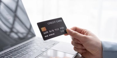 Ruka drží před notebookem kreditní kartu