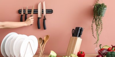 Pohled na kuchyňskou linku s nádobím, stojanem na nože a magnetickou lištou na nože