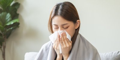 Nemocná žena si utírá nos kapesníkem