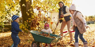 Rodina uklízí spadané listí na zahradě