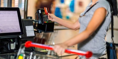 Žena platí kartou u samoobslužné pokladny.