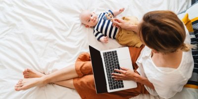 Matka s notebookem v klíně ukazuje hračku miminku