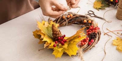 Žena tvoří dušičkový věnec z jeřabin, šišek a listů