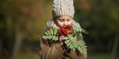 Holčička v zimním oblečení držící trs jeřabin
