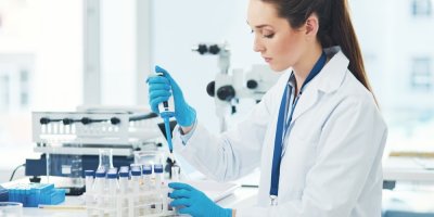 Vědkyně nabírá látku pipetou v laboratoři